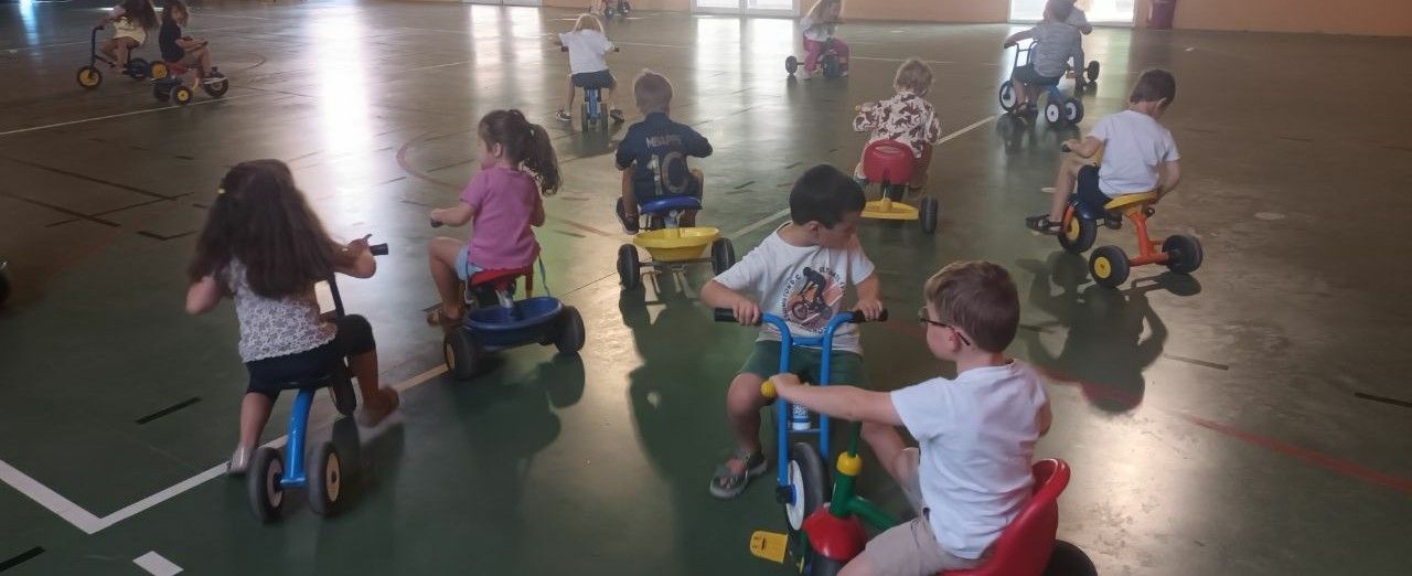 Enfants de maternelle utilisant des engins roulants sur un parcours